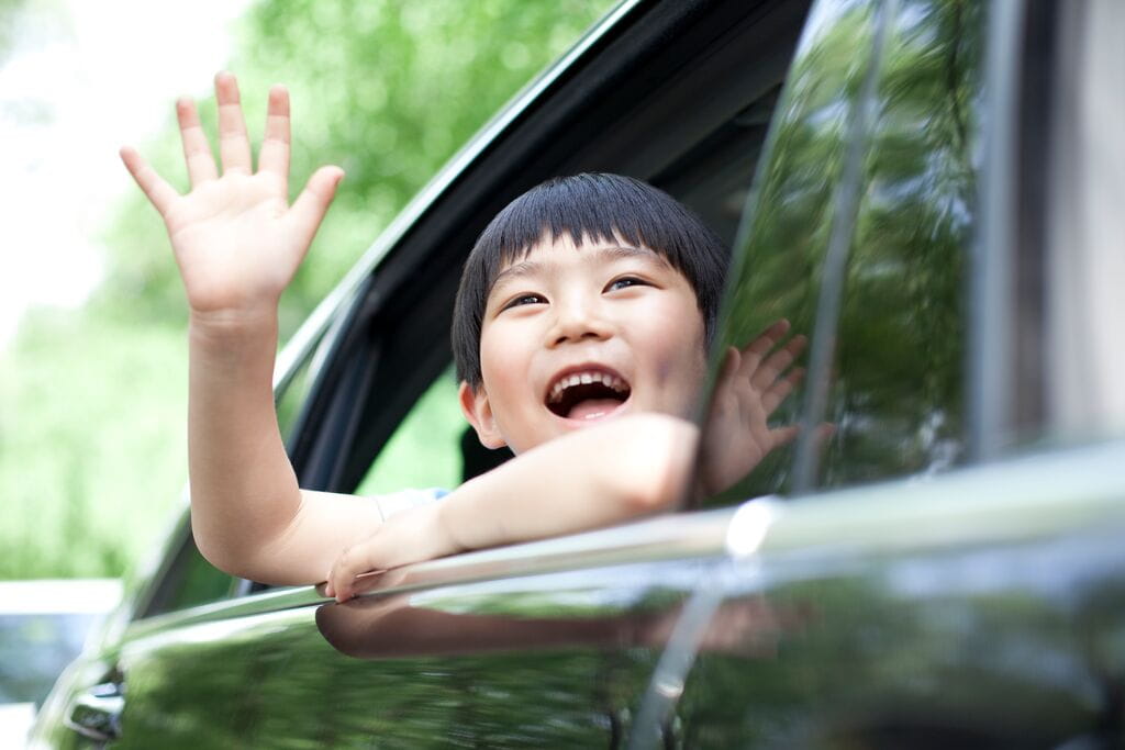 Criança a dizer adeus dentro de um carro