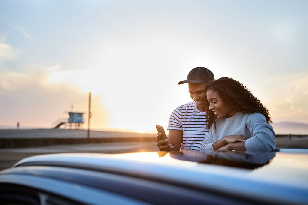 Casal perto do carro com o telemóvel