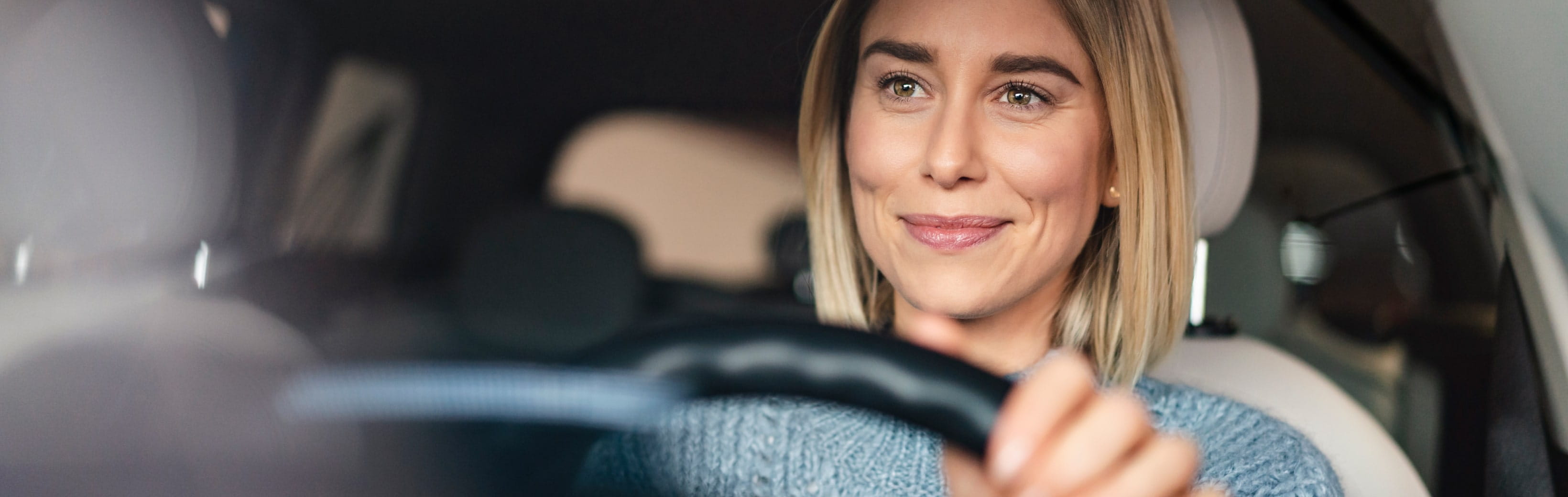 Hero-blonde-lady-smiling-inside-car-min